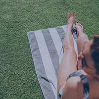 Frau entspannt auf Liegewiese im Freibad