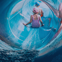 Kinder rutschen durch blaue Wasserrutsche